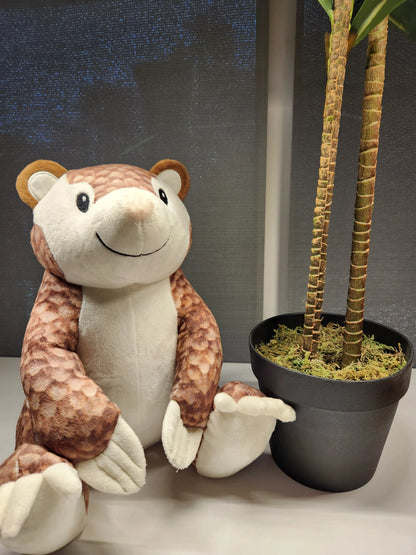 custom pangolin plush stuffed animal sitting next to a potted plant