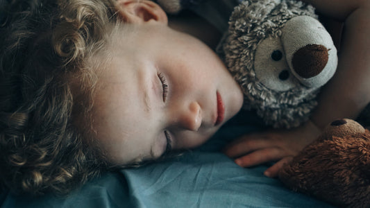 A child sleeping cuddled up next to some stuffed animals