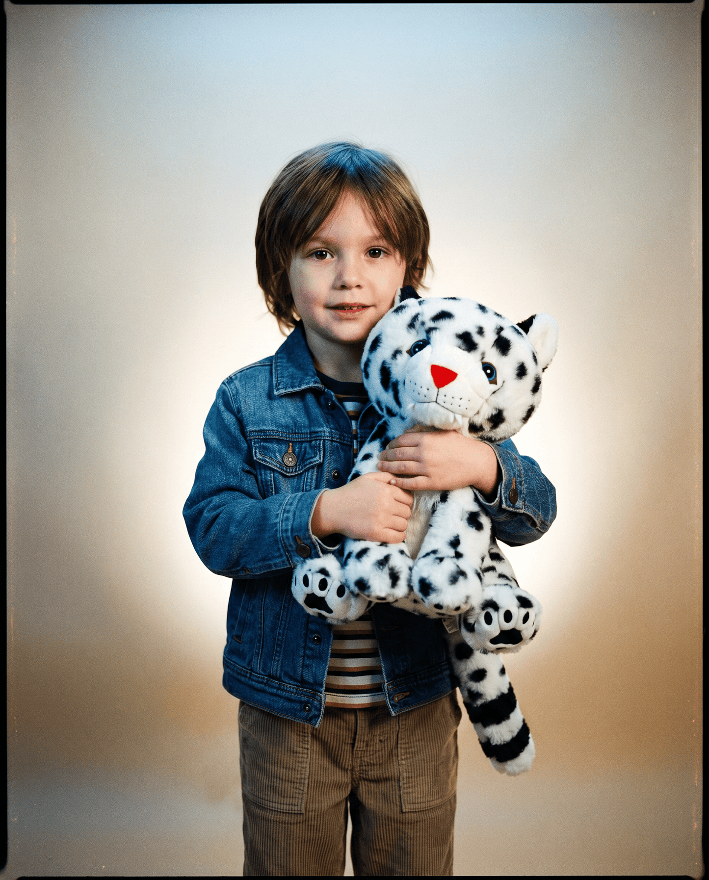 Child holding a snow leopard stuffed animal with a plain background