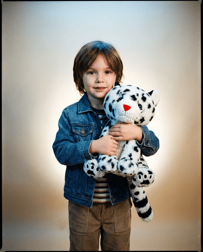 Child holding a snow leopard stuffed animal with a plain background