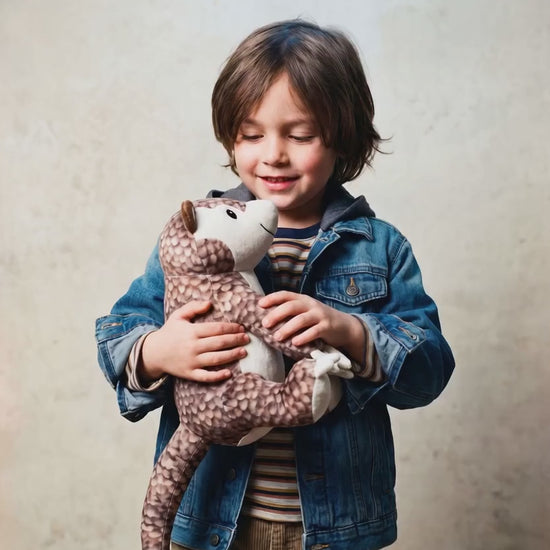 Child hugging Paulie the pangolin plush stuffed animal